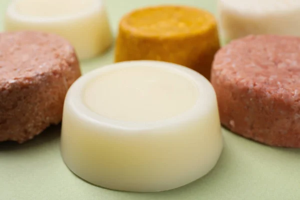 Group of solid shampoo bars on green table, closeup. Hair care