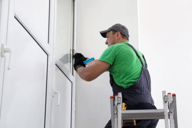 Katlama merdiveni üzerine çalışan işçiler pencereyi içeri kuruyor