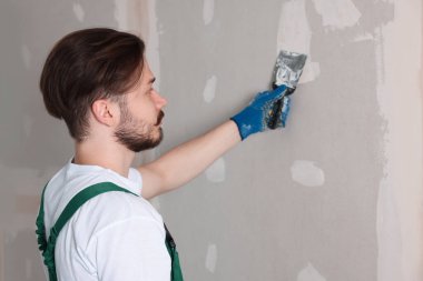 Üniformalı işçiler duvarları sıva ile kaplıyor.