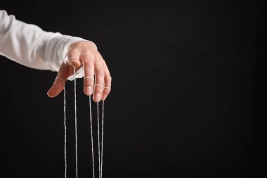 Siyah arka planda kukla ipleri elinde tutan kadın, yakın plan. Metin için boşluk