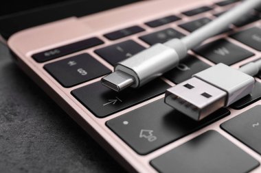 Koyu masa üzerinde C tipi bağlantı ve dizüstü bilgisayarı olan USB kablosu, yakın plan