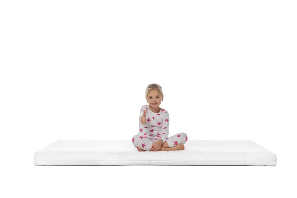 Kleines Mädchen Sitzt Auf Matratze Und Zeigt Daumen Nach Oben — Stockfoto
