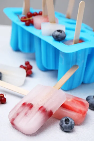 Tasty berry ice pops on light table, closeup