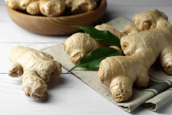 Fresh ginger with leaves on white wooden table