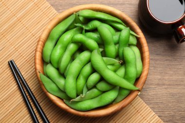 Tahta masada soya sosuyla servis edilen kabuklu yeşil edamame fasulyeleri.