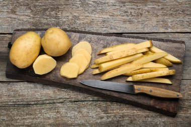 Ahşap masanın üstünde patatesleri bıçakla kesip biçmek. Lezzetli patates kızartması pişiriyorum.