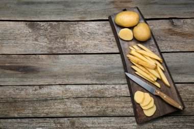 Patates ve bıçak ahşap masada, üst manzarada yazı için yer var. Lezzetli patates kızartması pişiriyorum.