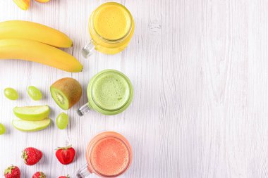 Beyaz ahşap masa üzerinde bir sürü lezzetli meyve püresi ve malzeme var. Metin için boşluk