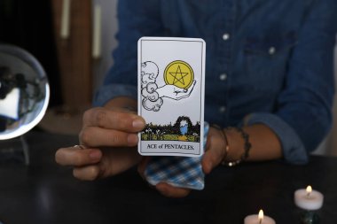 Elinde tarot kartı olan falcı. Gri masadaki beş köşeli yıldız, yakın plan.