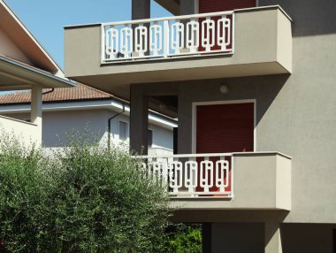 Güneşli bir günde balkonlu bir apartmanın dışı.