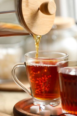 Pouring delicious tea into glass cup on table, closeup