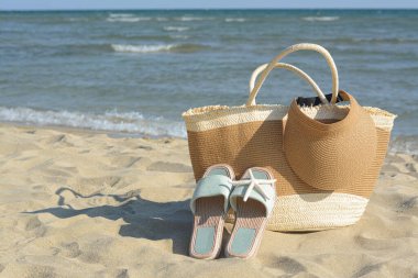 Terlikli şık çanta, güneşlik ve kuru denizyıldızı sahile yakın kumsalda, mesaj için yer var.