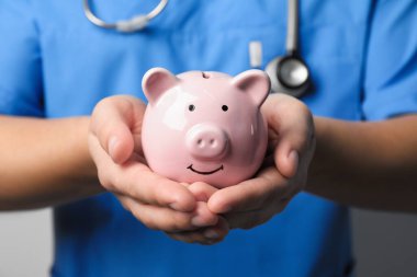 Doktor kumbarayı elinde tutuyor, yakın plan. Sağlık sigortası