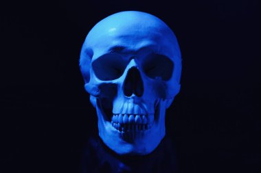 Blue human skull with teeth on black background clipart