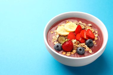 Taze böğürtlen, muz ve açık mavi arka planda tahıl gevreği ile nefis bir smoothie kasesi. Metin için boşluk