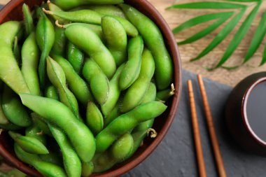Tahta masada soya sosuyla servis edilen kabuklu yeşil edamame fasulyeleri.