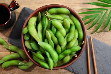 Tahta masada soya sosuyla servis edilen kabuklu yeşil edamame fasulyeleri.
