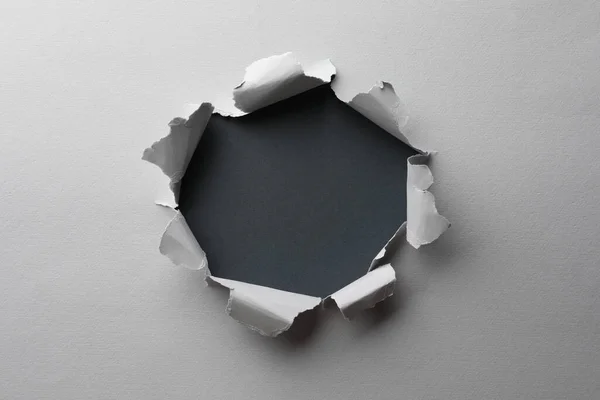 stock image Hole in white paper on black background