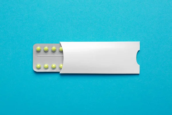 Birth control pills on light blue background, top view