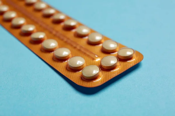 Birth control pills on light blue background, closeup
