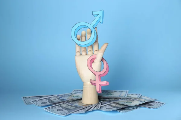 stock image Gender pay gap. Wooden mannequin hand with symbols and dollar banknotes on light blue background