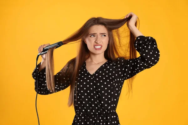 Стрессовая Молодая Женщина Плоским Железом Желтом Фоне Повреждение Волос — стоковое фото