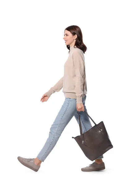 快乐的年轻女子 背着时髦的手提包走在白色的背景上 — 图库照片