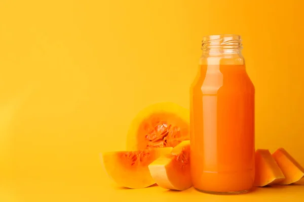 ガラス瓶でおいしいカボチャジュースとオレンジの背景にカボチャをカット テキストのスペース — ストック写真