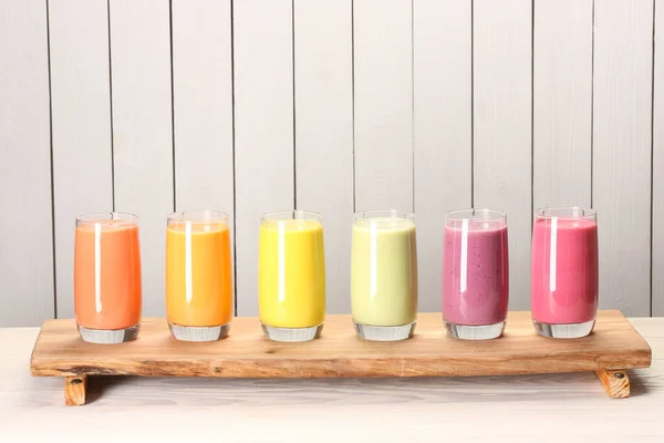 stock image Board with many different tasty smoothies against white wooden background, space for text