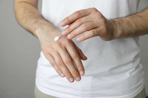 Άνδρας Που Απλώνει Κρέμα Στο Χέρι Πάνω Γκρι Φόντο Κοντινό — Φωτογραφία Αρχείου