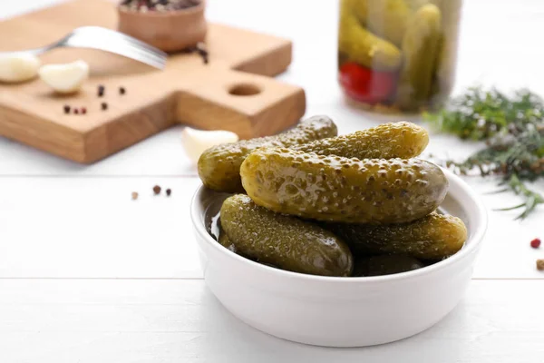 Tasty pickled cucumbers on white wooden table, space for text