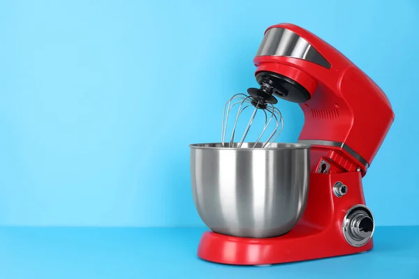 Modern red stand mixer on turquoise background, space for text