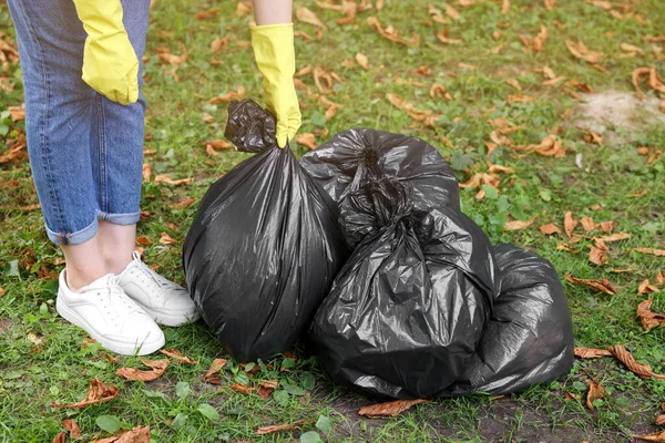 stock image Woman holding plastic bags with garbage in park, closeup.