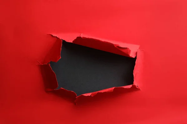 stock image Hole in red paper on black background