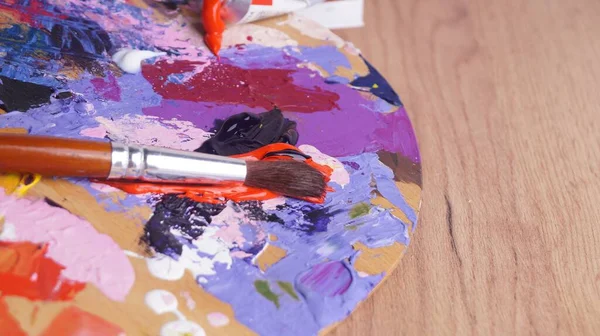 탁자에 페인트와 붓으로 뒤섞인 예술가의 팔레트 클로즈업 — 스톡 사진