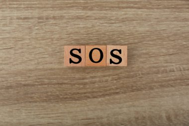 Ahşap arkaplandaki küplerden oluşan kısaltma SOS, üst görünüm