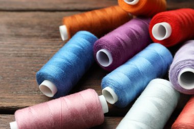 Ahşap masaya farklı renkte dikiş iplikleri, yakın plan.