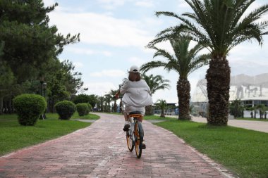 Young woman riding bicycle on lane outdoors, back view