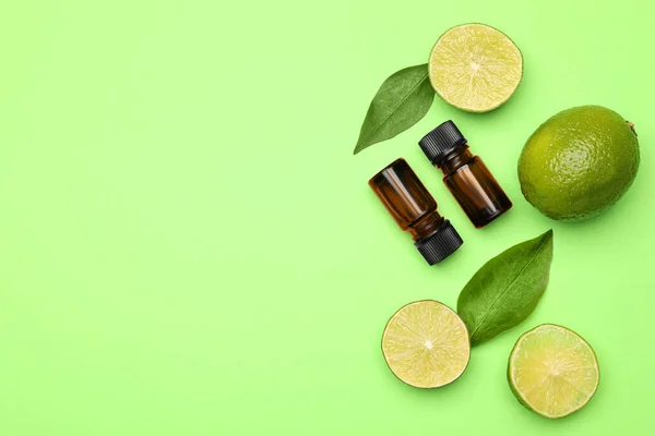 Flaschen Mit Ätherischem Zitrusöl Und Frischen Limetten Auf Grünem Hintergrund — Stockfoto