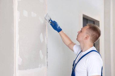Duvara macun bıçağıyla sıva yapan bir adam. Ev yenilenmesi