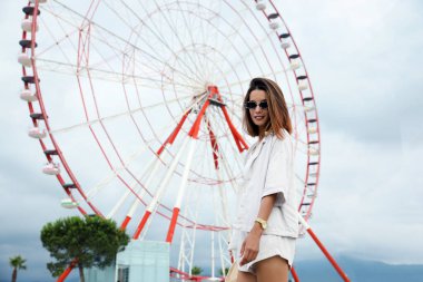 Beautiful young woman near Ferris wheel outdoors