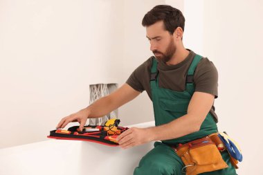 Elektrikçi, alet çantasından tornavidayı içeri alıyor.
