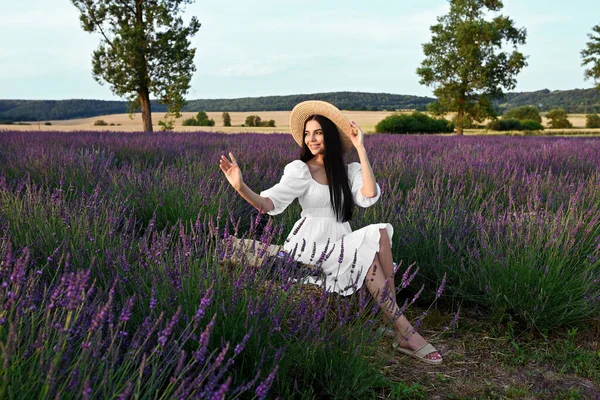 Beautiful young woman sitting in lavender field