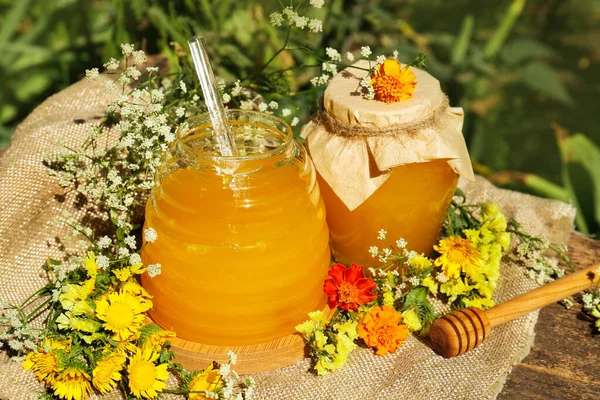 おいしい新鮮な蜂蜜と木製のテーブルの上の美しい花 — ストック写真