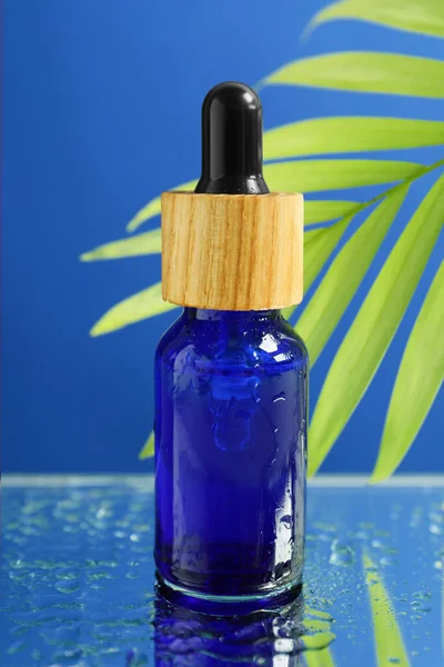 Fles Gezichtsserum Nat Oppervlak Tegen Blauwe Achtergrond Close — Stockfoto