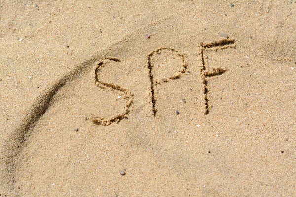 stock image Abbreviation SPF written on sand at beach, above view