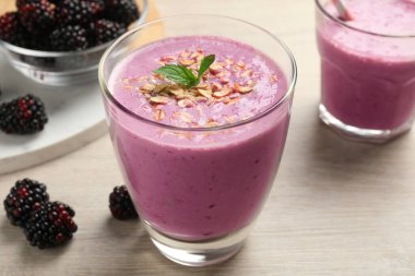 Beyaz ahşap masada yulaf ezmeli lezzetli böğürtlen smoothie, yakın plan.