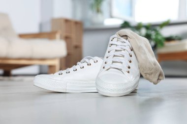 Beyaz ahşap zeminde kirli çorapları olan spor ayakkabıları.