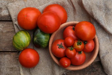 Many different ripe tomatoes on wooden table, flat lay