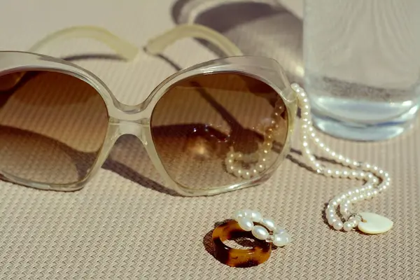 Stylowe Okulary Przeciwsłoneczne Szklanka Wody Biżuteria Szarej Powierzchni Zbliżenie — Zdjęcie stockowe